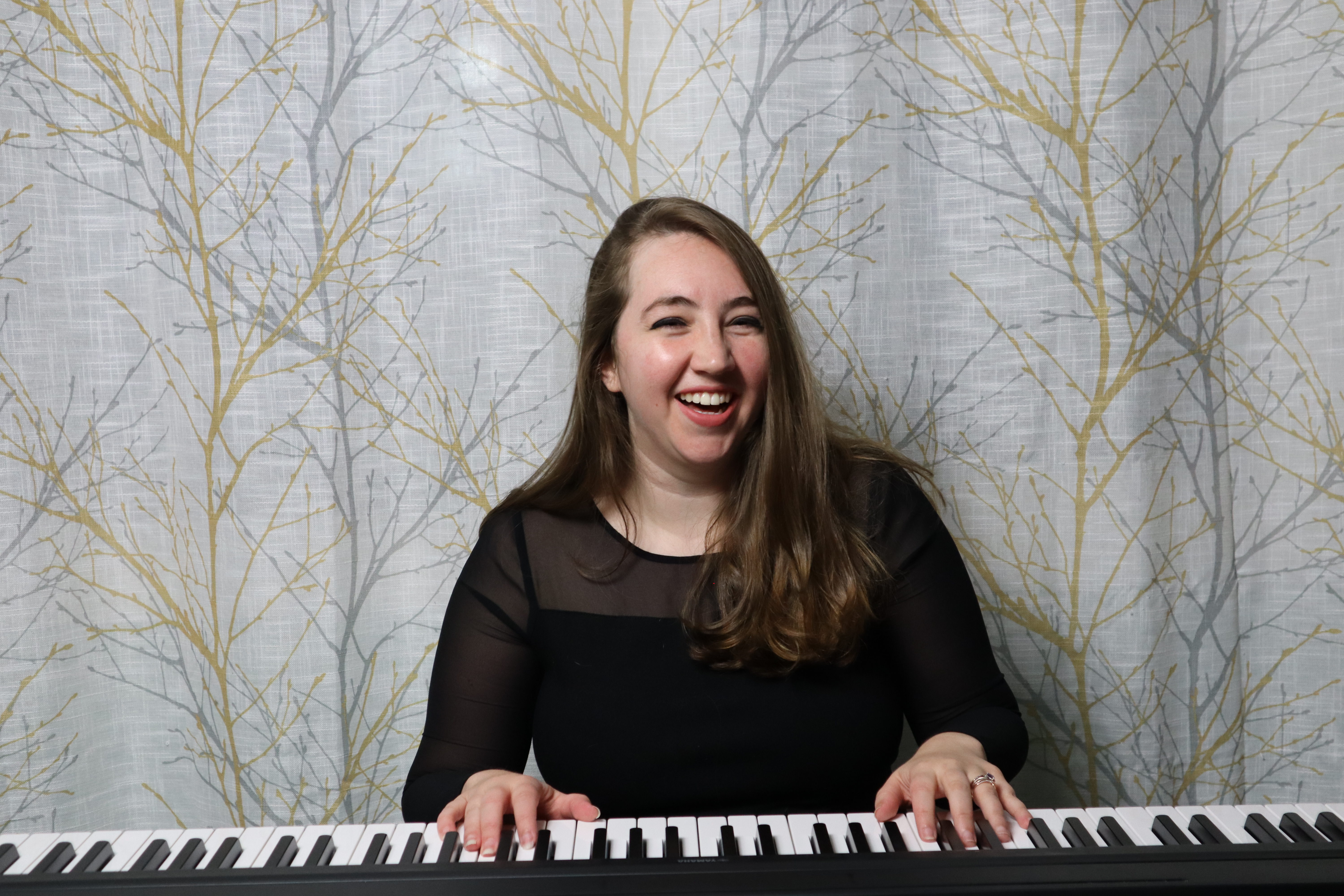 April Keez laughing while playing the piano